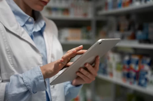 Farmacéutico revisando el stock de inventario en estantería de farmacia moderna.