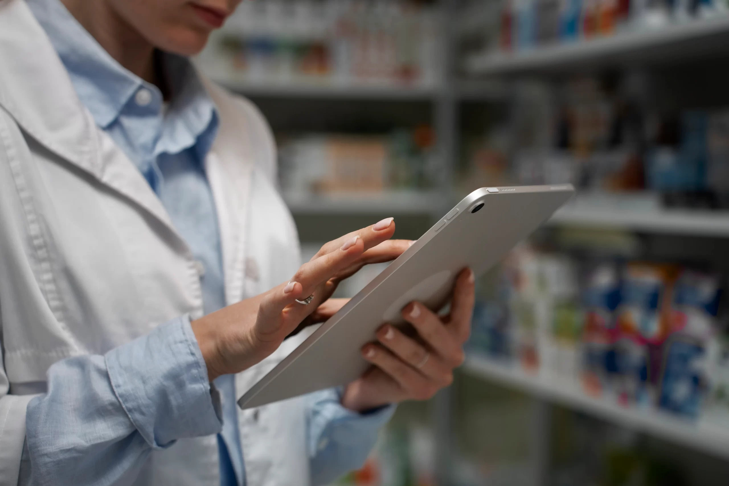 Farmacéutico revisando el stock de inventario en estantería de farmacia moderna.