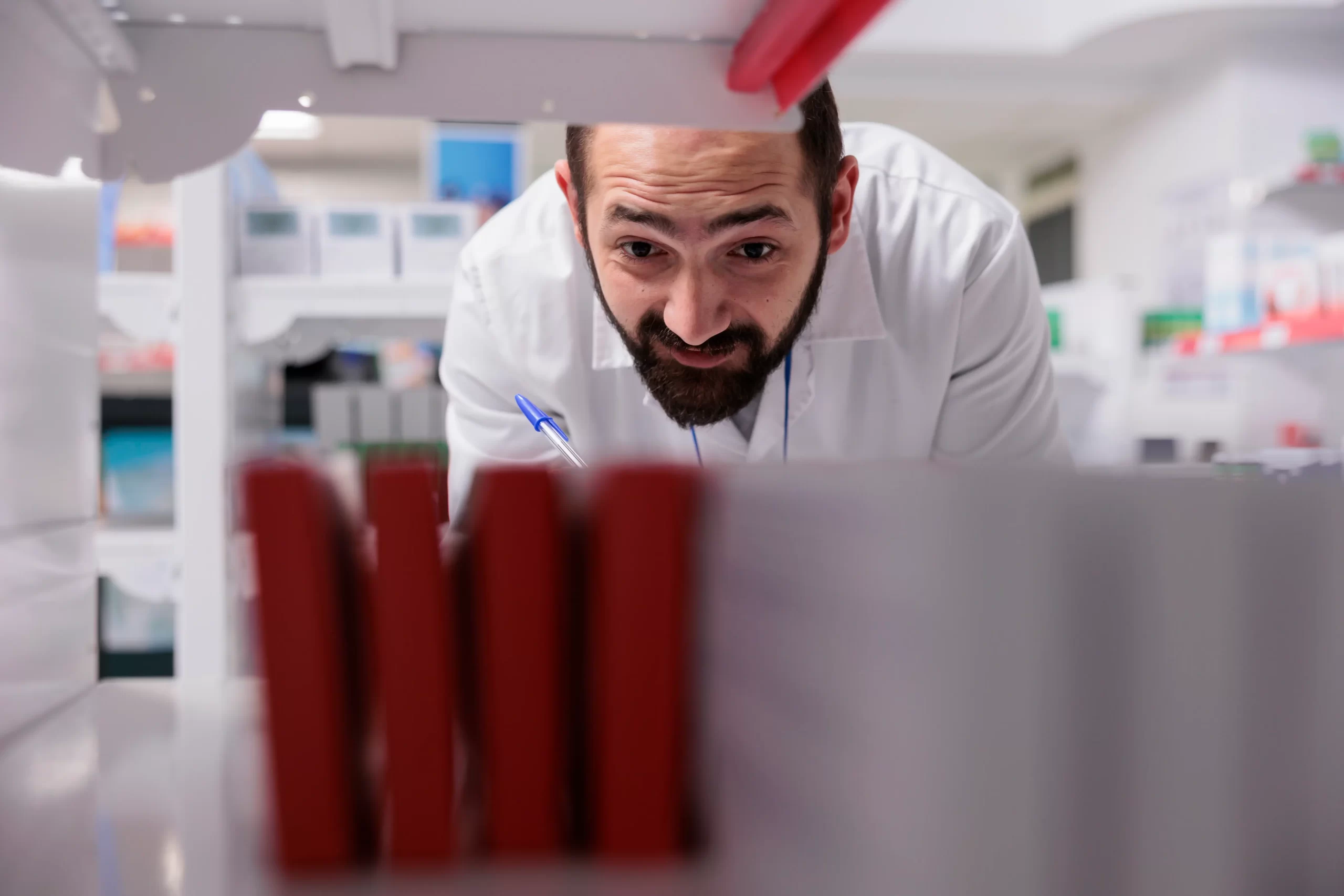 Farmacéutico analizando cajas de productos para clasificar entre medicamentos, cosméticos y complementos para una campaña de publicidad.