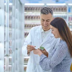 Farmacéutica asesorando a un cliente sobre productos complementarios durante una venta cruzada en farmacia.